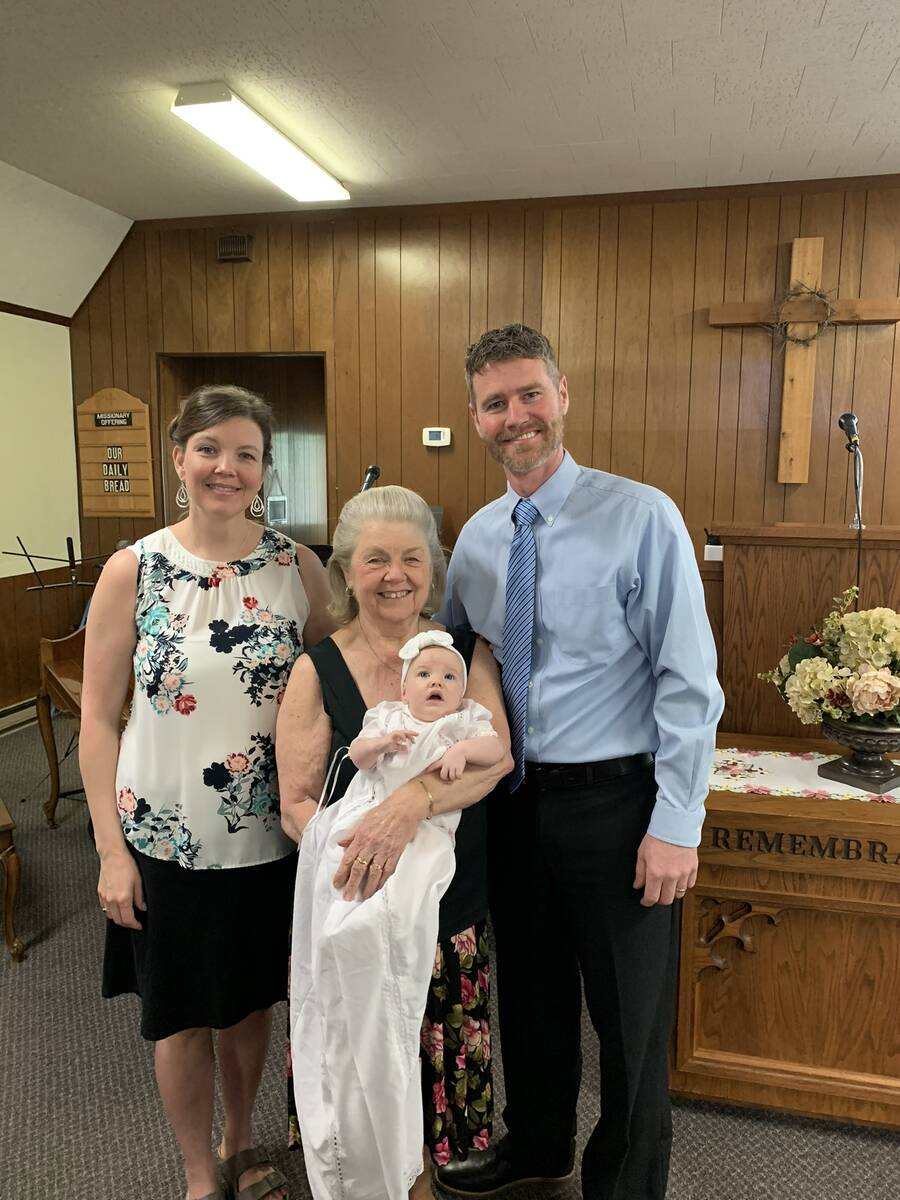 Parents and grandmother posing with the baby after the dedication