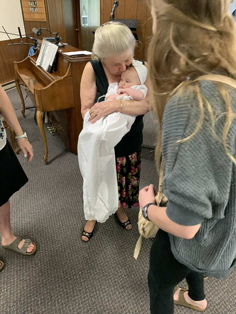 Grandmother kissing the baby while friends gather around