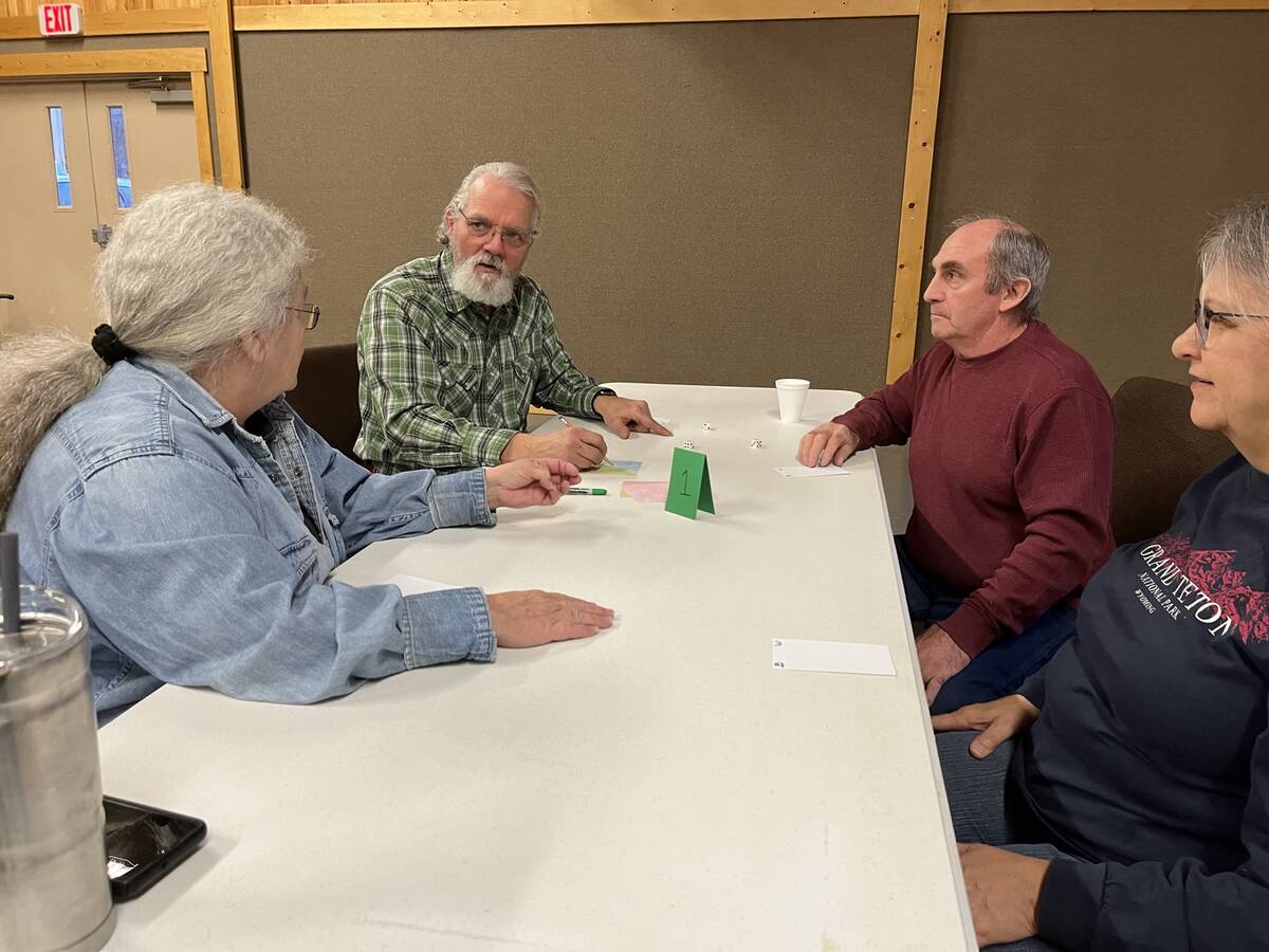 Older members playing a card game at a long table