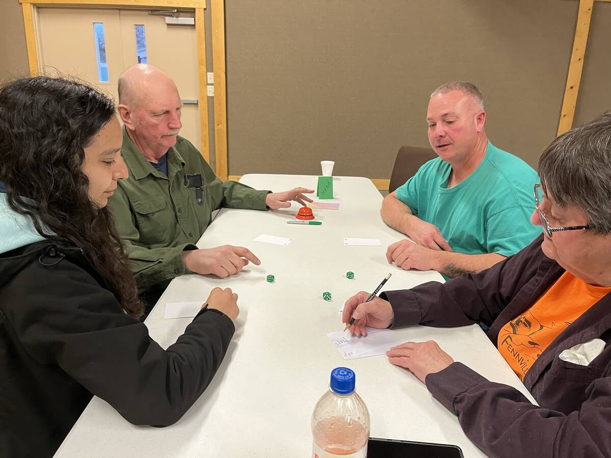 Adults and teens laughing over a game at the table