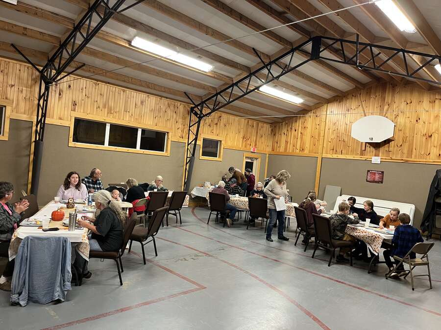 Wide view of the fellowship hall filled with tables for a church dinner