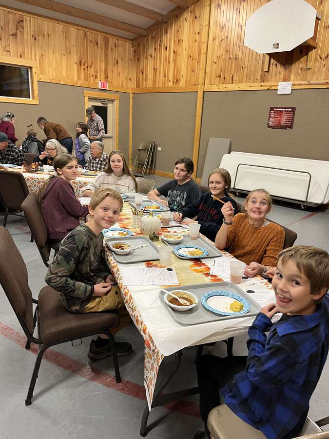 Kids smiling at a long table during a fall dinner