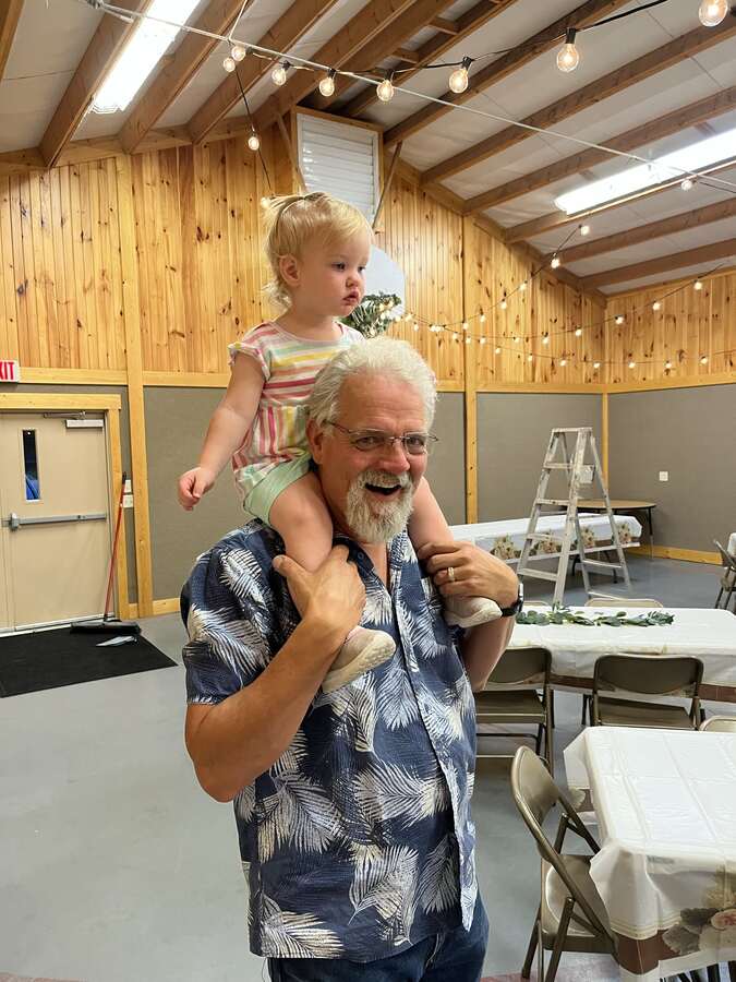 Man carrying a toddler on his shoulders in the fellowship hall