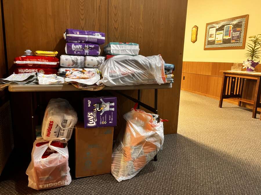 Table piled with diapers, wipes, and baby supplies collected by the church