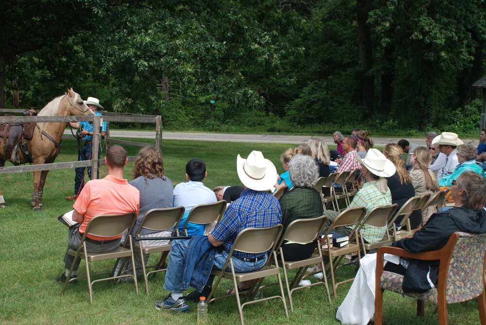 Folks in cowboy hats watching from lawn chairs beside the round pen