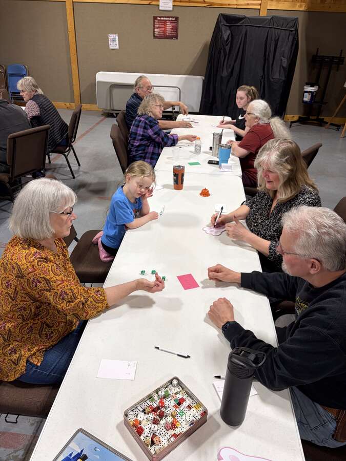Long table of players rolling dice and keeping score at game night